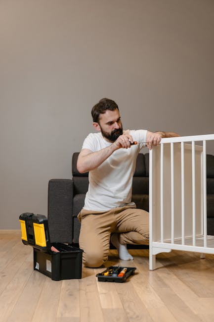A father kneels beside a crib using tools, representing parenting and home life.